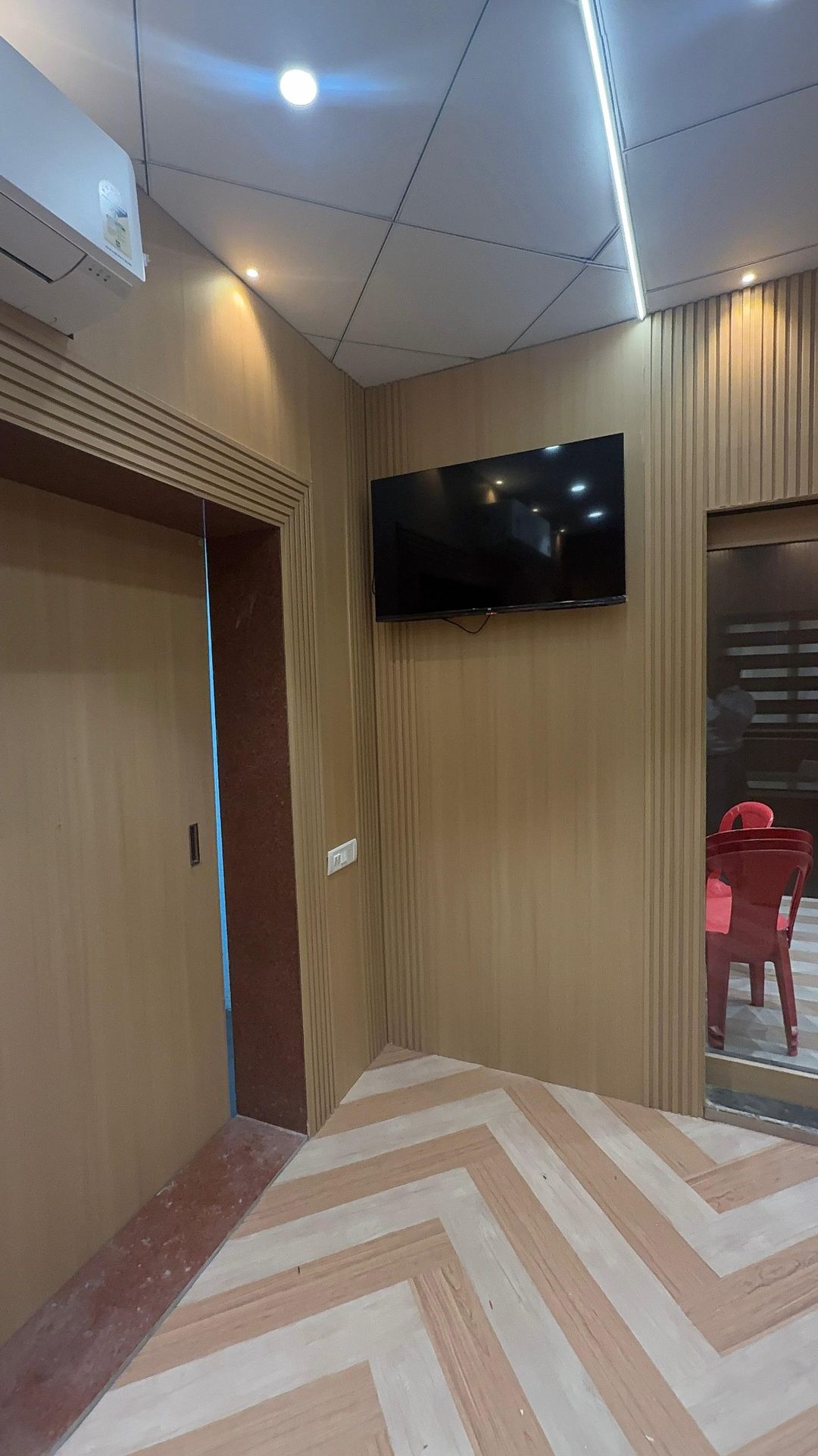 Wood panel TV wall installation with herringbone flooring