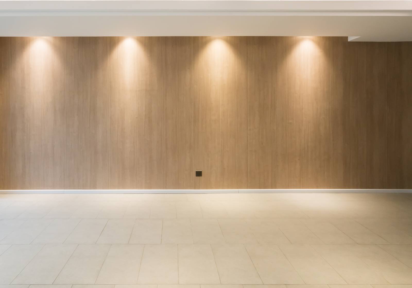 Plain wood-look panelled wall lit by downlights