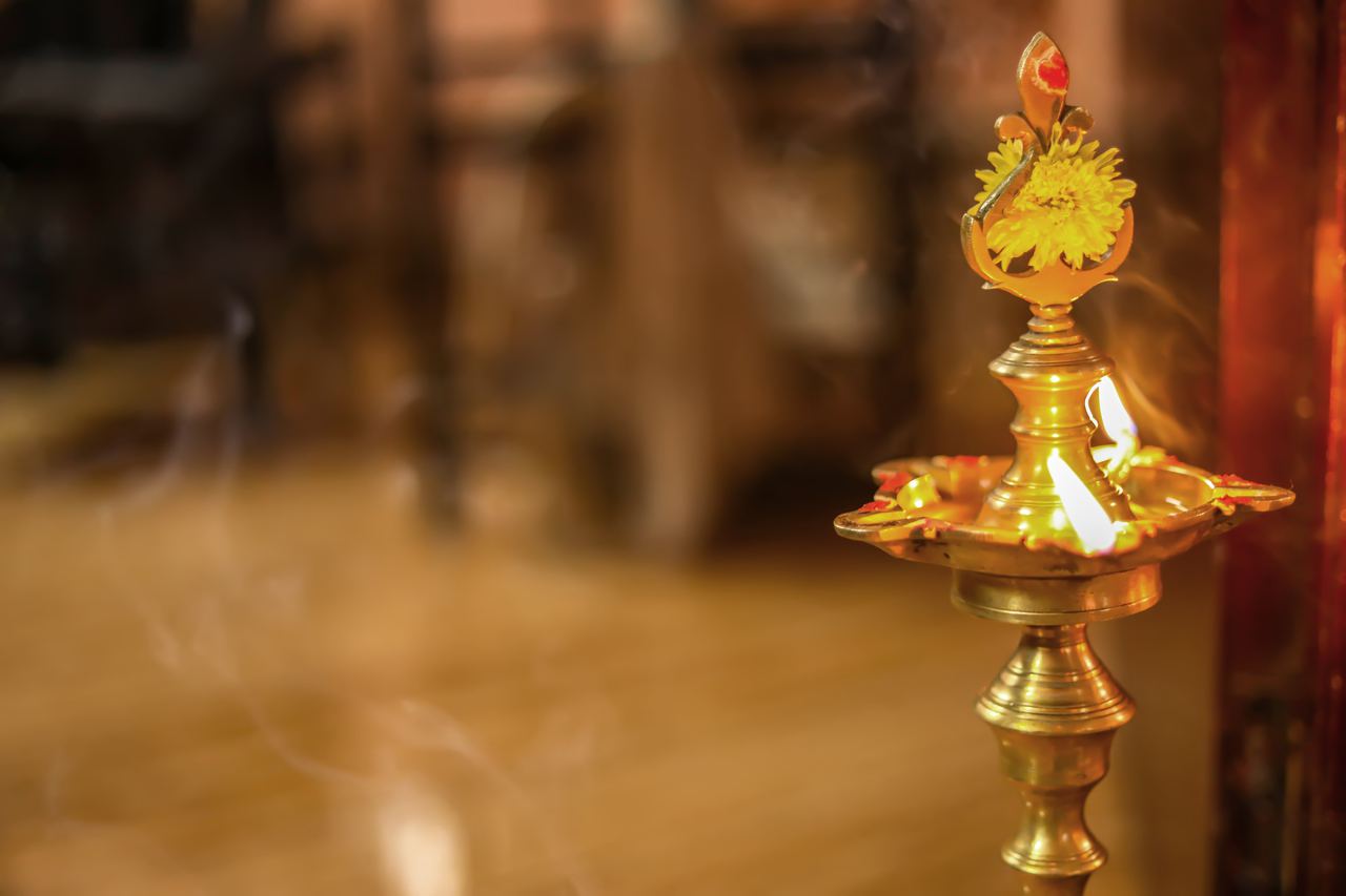 Traditional brass oil lamp lit in a pooja room