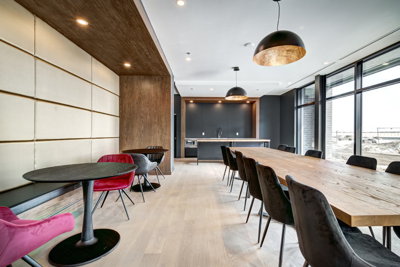 Office breakout area with a timber-panelled wall and long tables