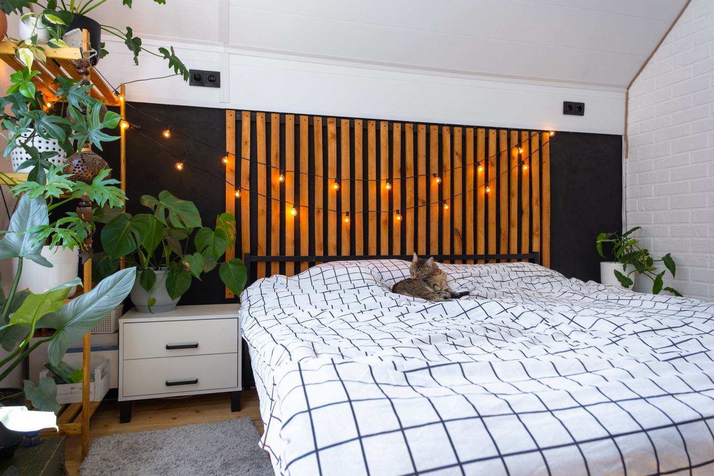 Warm wooden louver slats fixed vertically behind a bed as a full-height headboard feature wall