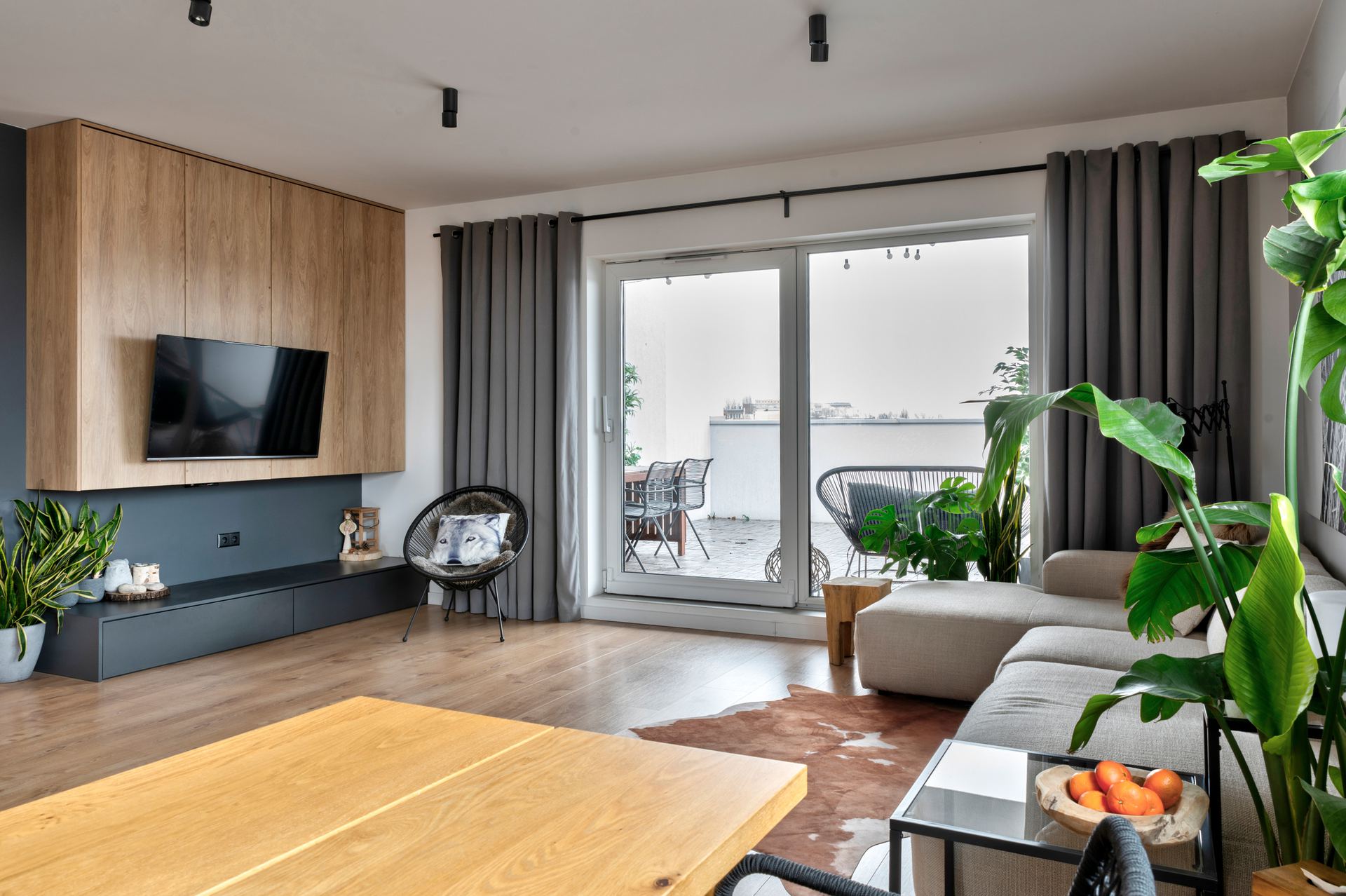 Modern living room with a warm wood-panelled TV wall, a wall-mounted television and a grey sofa