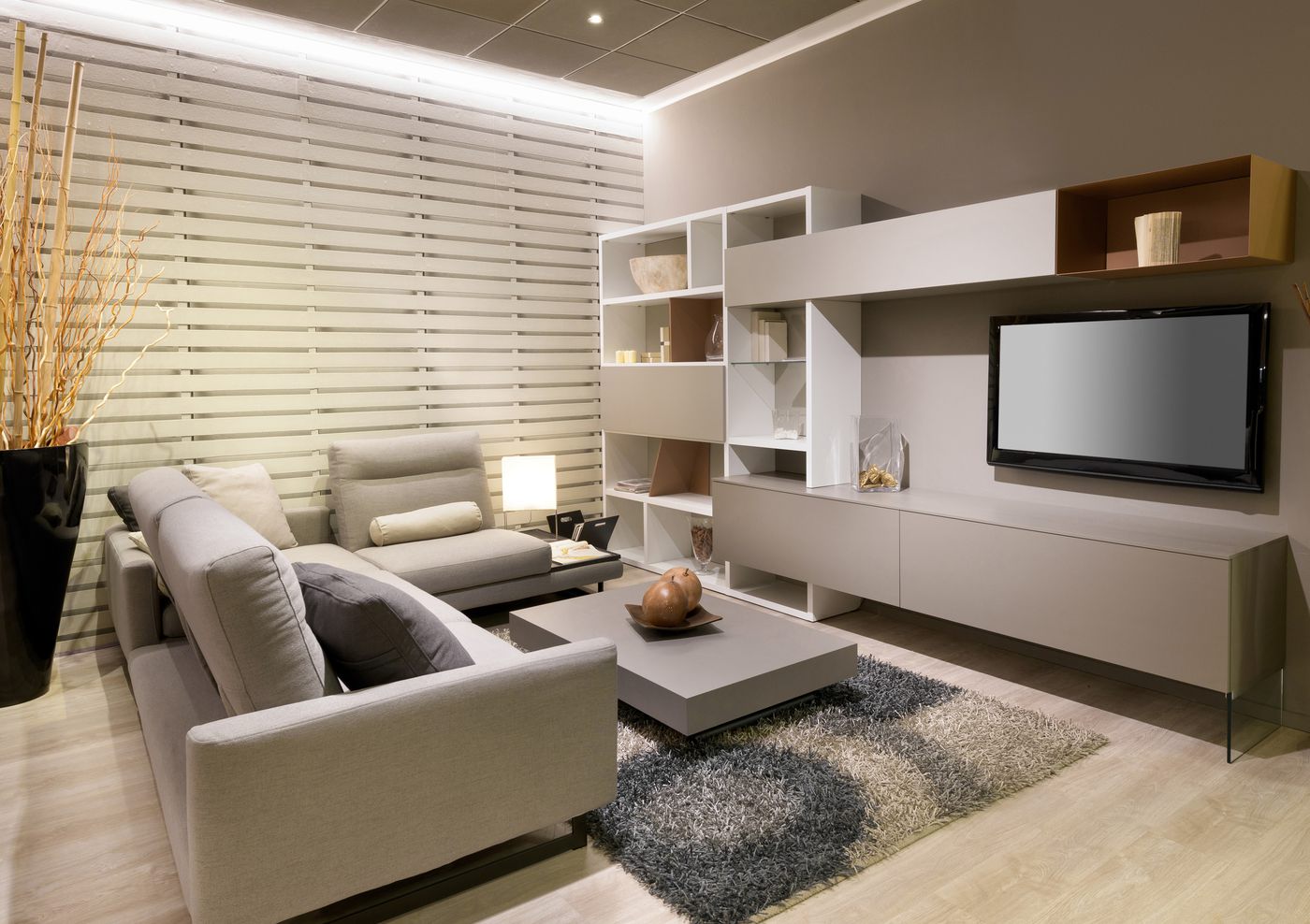 Living room with horizontal wood-look slats on one wall, a wall-mounted TV unit and warm cove lighting