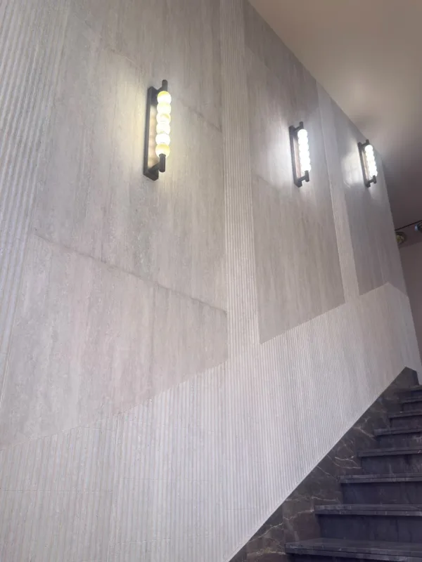 SoftIQ plain and fluted soft stone along a staircase wall with wall lights in Lonavla, a real Urbane Decor installation